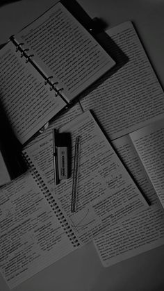 black and white photograph of notebooks, pen and paper