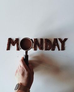 a person holding a magnifying glass in front of the word monday on a white wall