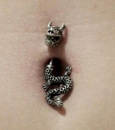 two silver charms sitting on the side of a woman's stomach, one with an animal head