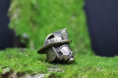 a silver ring sitting on top of a green moss covered ground