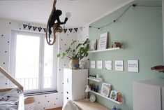 a bedroom with green walls and white decor on the wall, an animal statue hanging from the ceiling