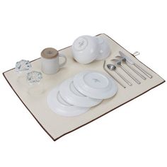 a place mat with plates, cups and spoons on it next to utensils