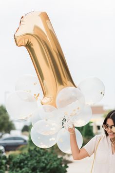 a woman is holding up balloons in the shape of a number