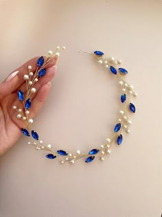 a woman is holding a blue and white beaded headband with pearls on it