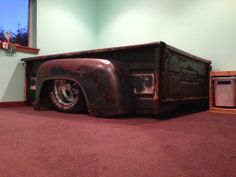 an old truck bed is sitting in the middle of a room with purple carpet and green walls