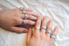 two hands holding onto each other's wedding rings on top of a white sheet