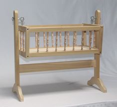 a baby crib with wooden posts and wood slats on the sides, against a white backdrop