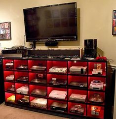 a large television mounted to the side of a wall next to a shelf filled with video game controllers