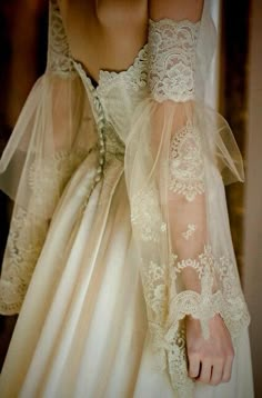 the back of a woman's wedding dress with sheer sleeves