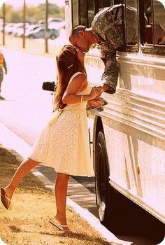 a man kissing a woman in front of a bus on the side of the road