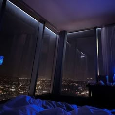 a bedroom with a large window overlooking the city lights at night and there is a television set in the corner