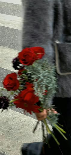 a woman is walking down the street with flowers in her hand