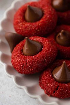 chocolate covered cookies on a plate with red sprinkles and candy in the middle