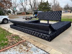 a large black bed sitting on top of a sidewalk