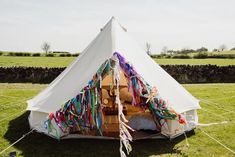 a large white tent with streamers hanging from it's sides in the grass