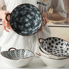 a person is holding three bowls in their hands and one bowl has an ornate design on it