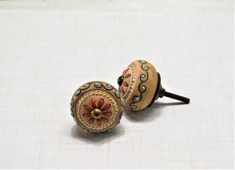 two wooden knobs with decorative designs on them sitting on a white cloth covered surface