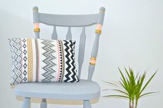 a chair with a pillow on it next to a potted plant