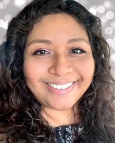 a woman with curly hair smiling at the camera