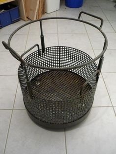 a metal basket sitting on top of a tiled floor