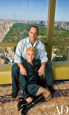 a man and woman sitting on the ground in front of a window with cityscape