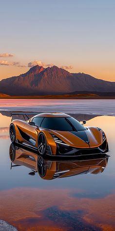 an orange sports car sitting on top of a body of water next to a mountain