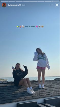 two young women sitting on the roof of a building