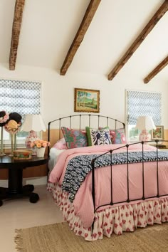 a bedroom with pink bedding and wooden beams