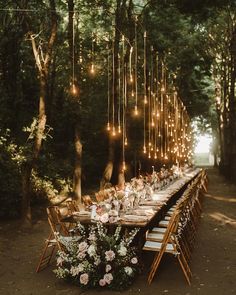 an outdoor dinner table with string lights strung from the trees and flowers on the tables