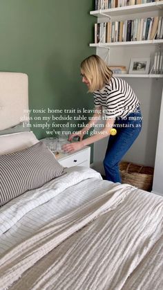 a woman in striped shirt leaning over a bed