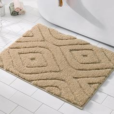 a bath room with a rug on the floor next to a tub and toilet paper