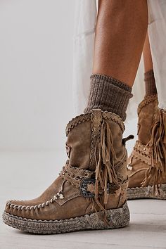 A unique pair with western-inspired flair, this moccasin-boot combo is featured in a funky leather design with fringe, buckles, embroidery, engraved soles, and a detailed patch. * Wedge heel * Covers ankle * Hand stitched detail * Durable rubber outsole | Arya Mocc Boots by El Vaquero at Free People in Tan, Size: EU 39 Casual Leather Moccasins With Fringe, Moccasin Boots Outfit, Bohemian Suede Boots With Fringe, Ranch Fashion, Brown Leather Fringe Boots, Fringe Moccasin Boots, Brown Fringe Winter Boots, Fringe Moccasins, Suede Fringe Boots