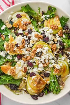 a white bowl filled with salad topped with pears and feta cheese on top