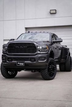 a large black truck parked in front of a garage door with two tires on it