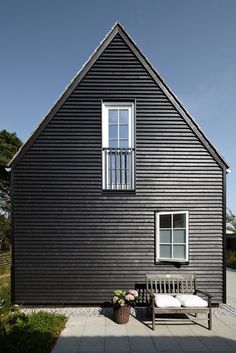 a black house with a white window and wooden bench