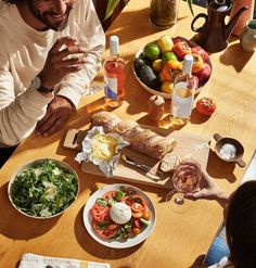 a group of people sitting around a wooden table eating food and drinking wine at a restaurant