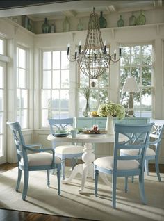 a dining room table with chairs and a chandelier hanging from the ceiling in front of windows