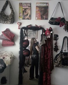 a woman standing in front of a mirror next to bags and purses on the wall