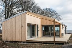 a small wooden house with sliding glass doors on the front and side windows that are open