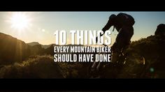 a man riding a mountain bike up the side of a hill with the sun in the background