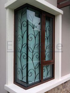 a window with decorative iron work on the glass and wood frame, in front of a brick wall