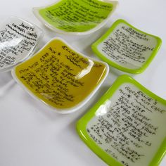 four small dishes with writing on them sitting next to each other in front of a white table