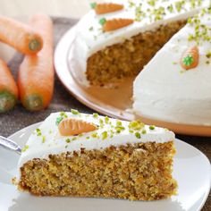 carrot cake with white frosting and green sprinkles on plate next to sliced carrots