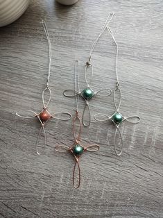 four pieces of wire and glass sitting on top of a wooden table next to a vase