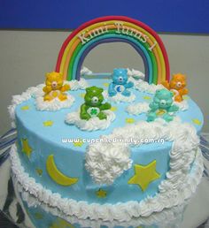 there is a blue cake with white frosting and teddy bears on the top it has a rainbow in the middle