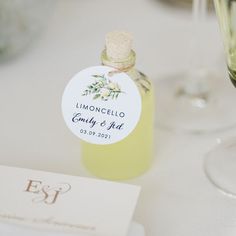 a bottle of liquid sitting on top of a table next to a glass filled with wine