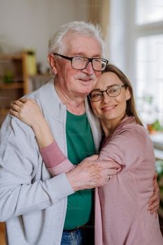 an older man and woman hugging each other