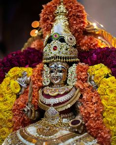 an idol is displayed in front of flowers on display at a festival, with lights behind it