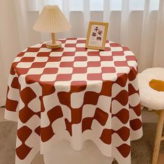 a table with a red and white checkered cloth on it next to a lamp