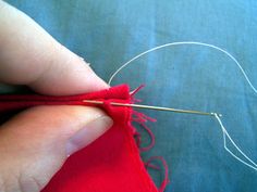 someone is stitching the thread on their red piece of fabric